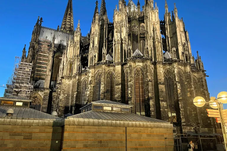 The Gothic east end of Cologne Cathedral (Kölner Dom) with its twin spires and flying buttresses against a deep blue evening sky