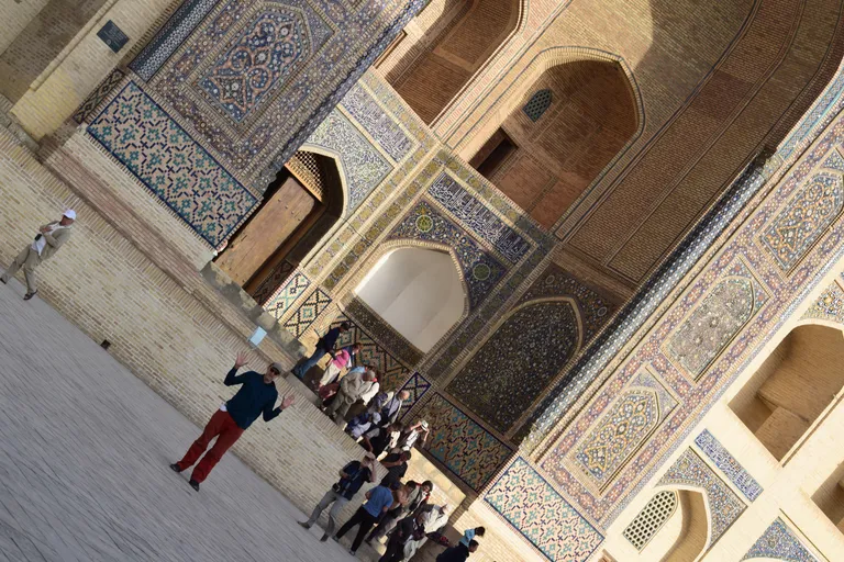 A traveler standing in Registan Square between the tiled madrasas of Samarkand