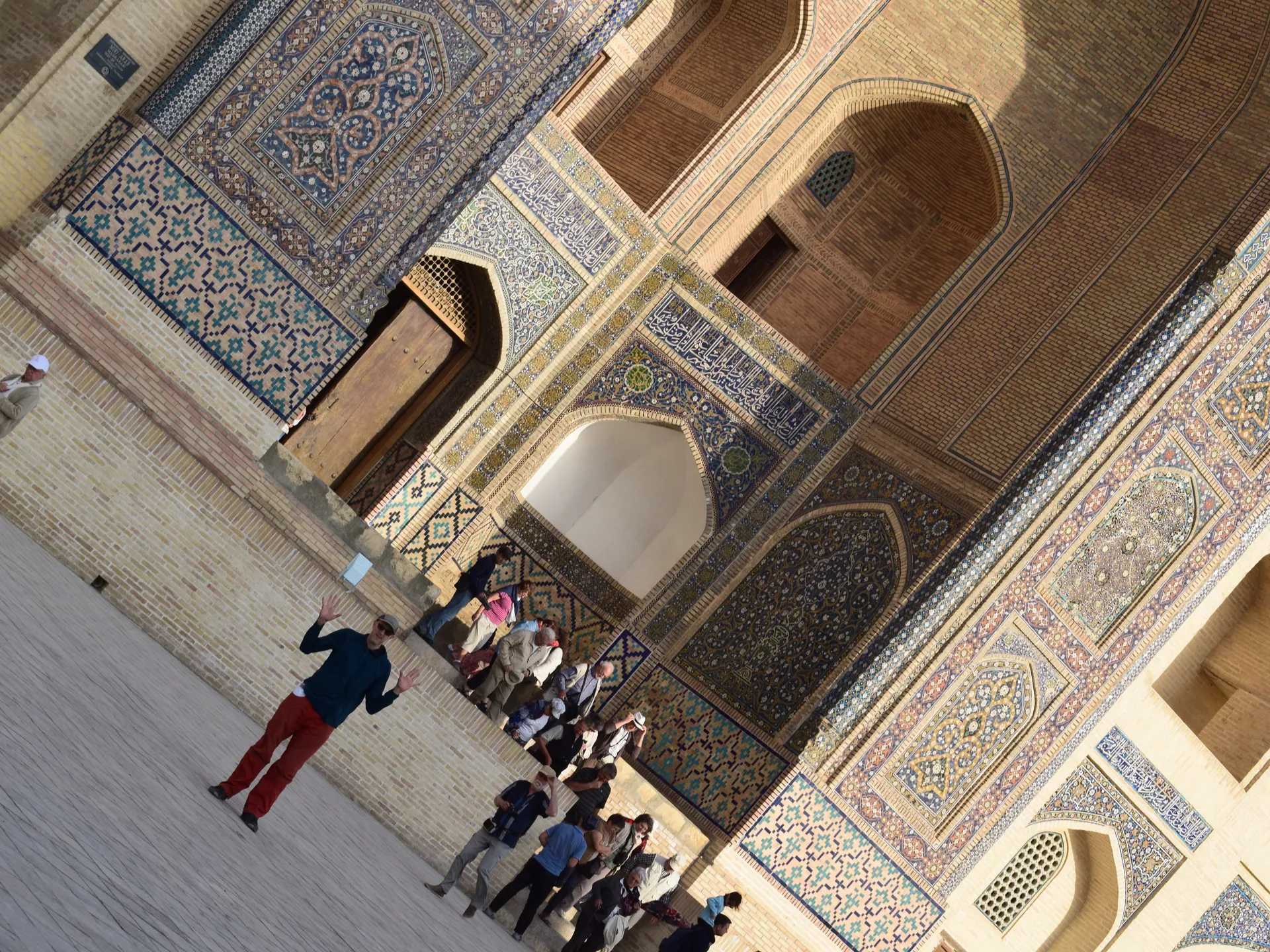 A traveler standing in Registan Square between the tiled madrasas of Samarkand
