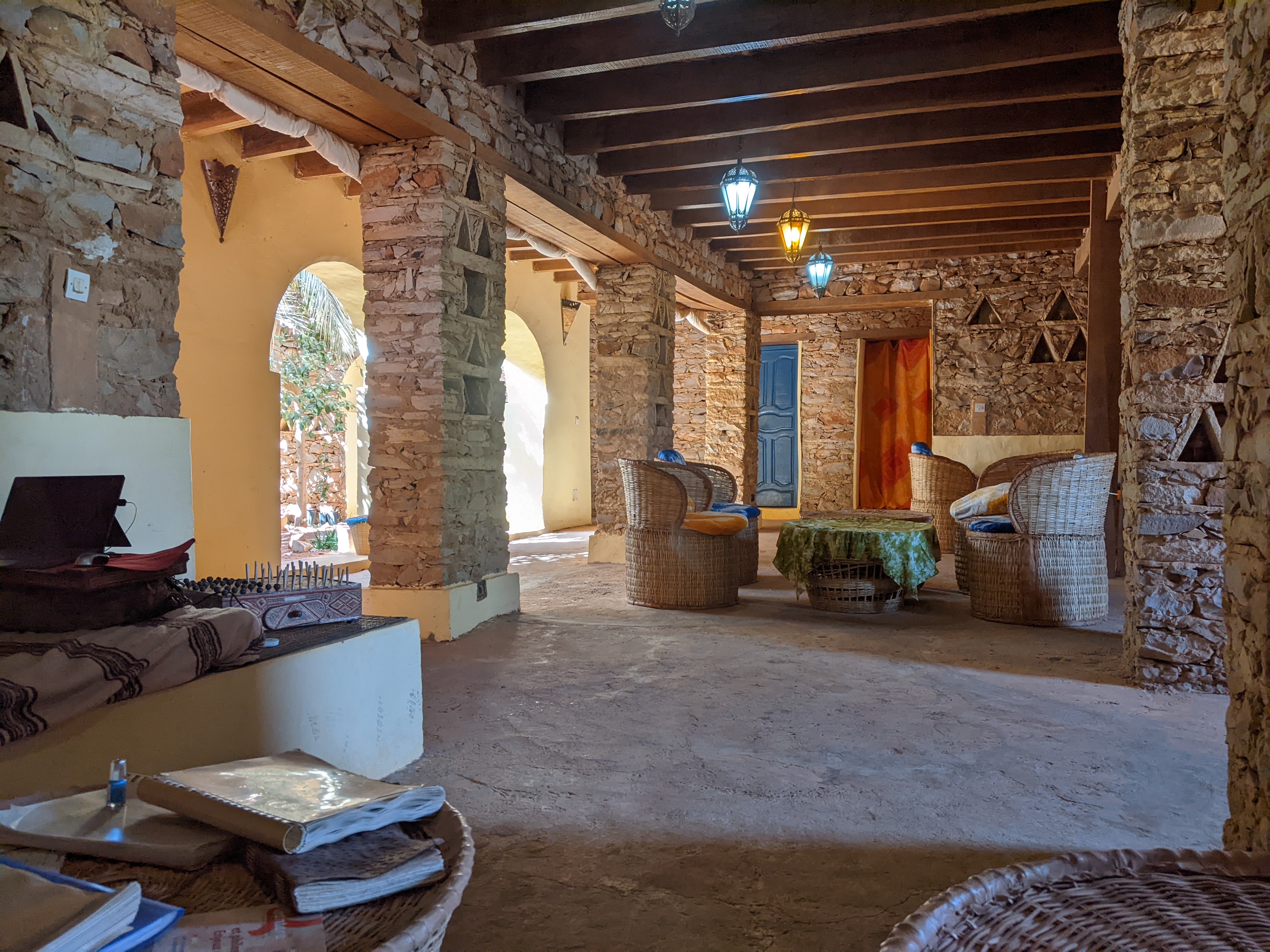 Stone guesthouse interior with woven chairs and lanterns in Chinguetti