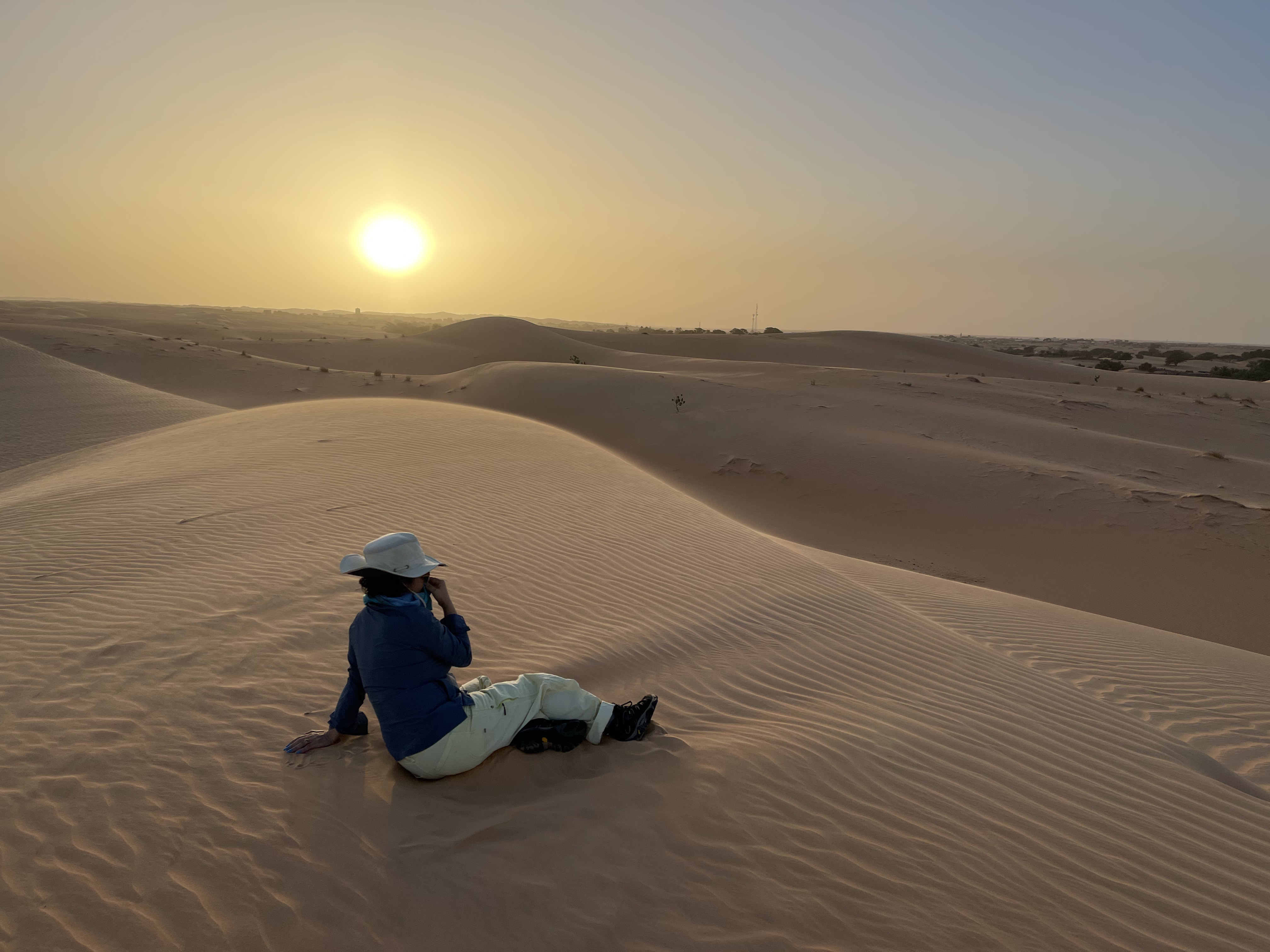 Traveller sitting on a sand dune near Chinguetti at sunset