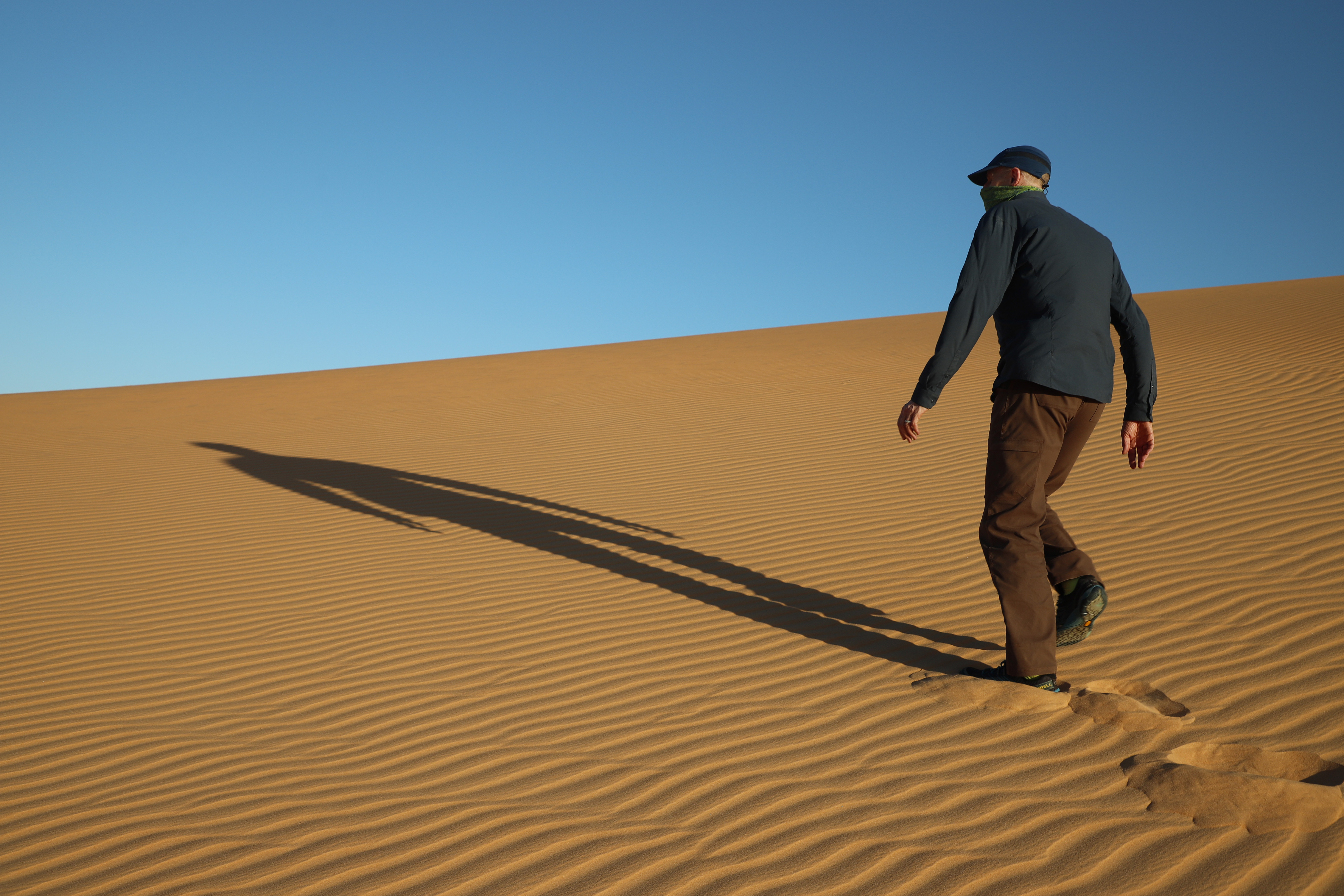 Person walking across a rippled sand dune near Chinguetti