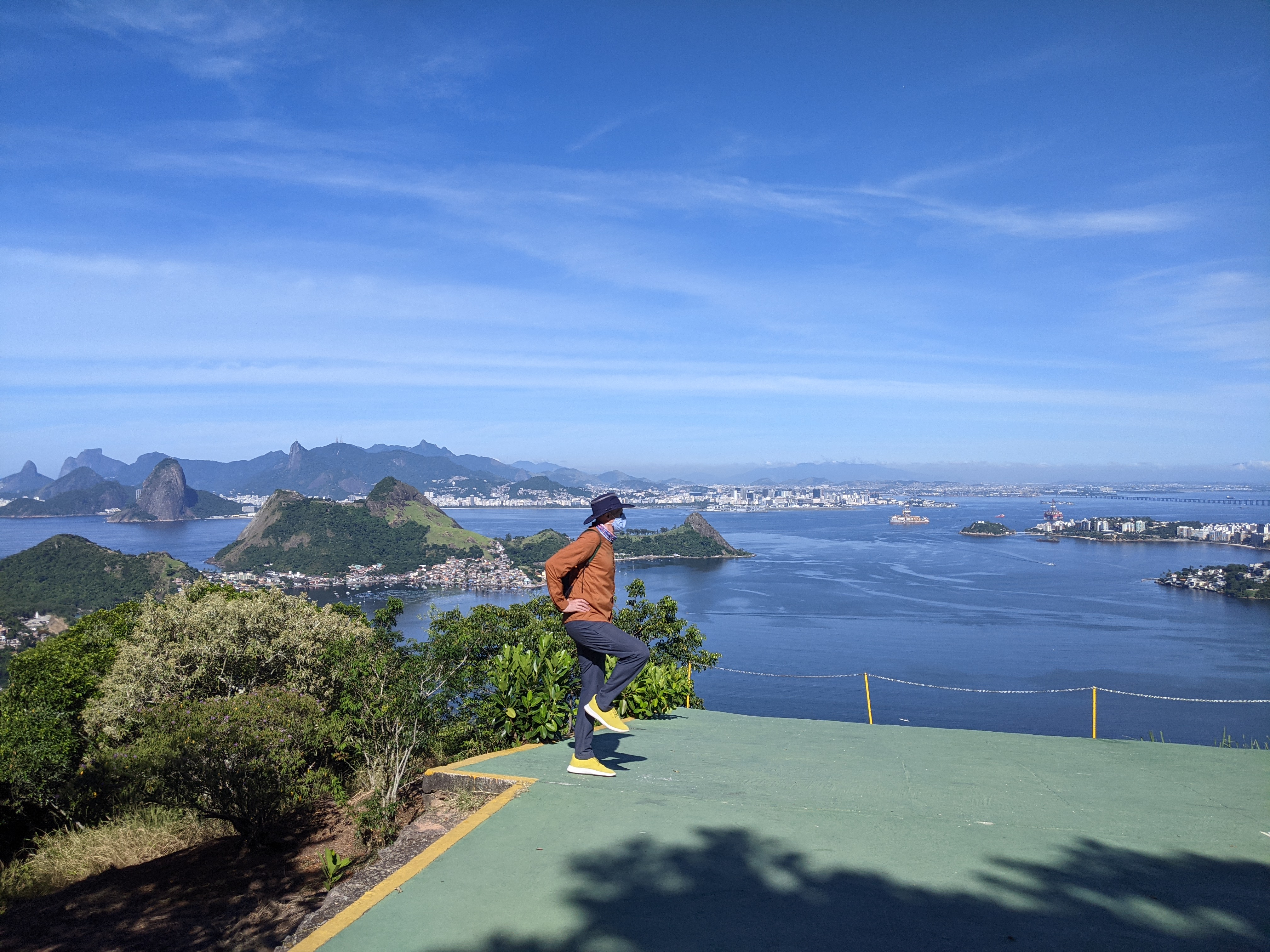 Traveller at a hilltop viewpoint looking across Guanabara Bay toward Sugarloaf Mountain and the Rio de Janeiro skyline