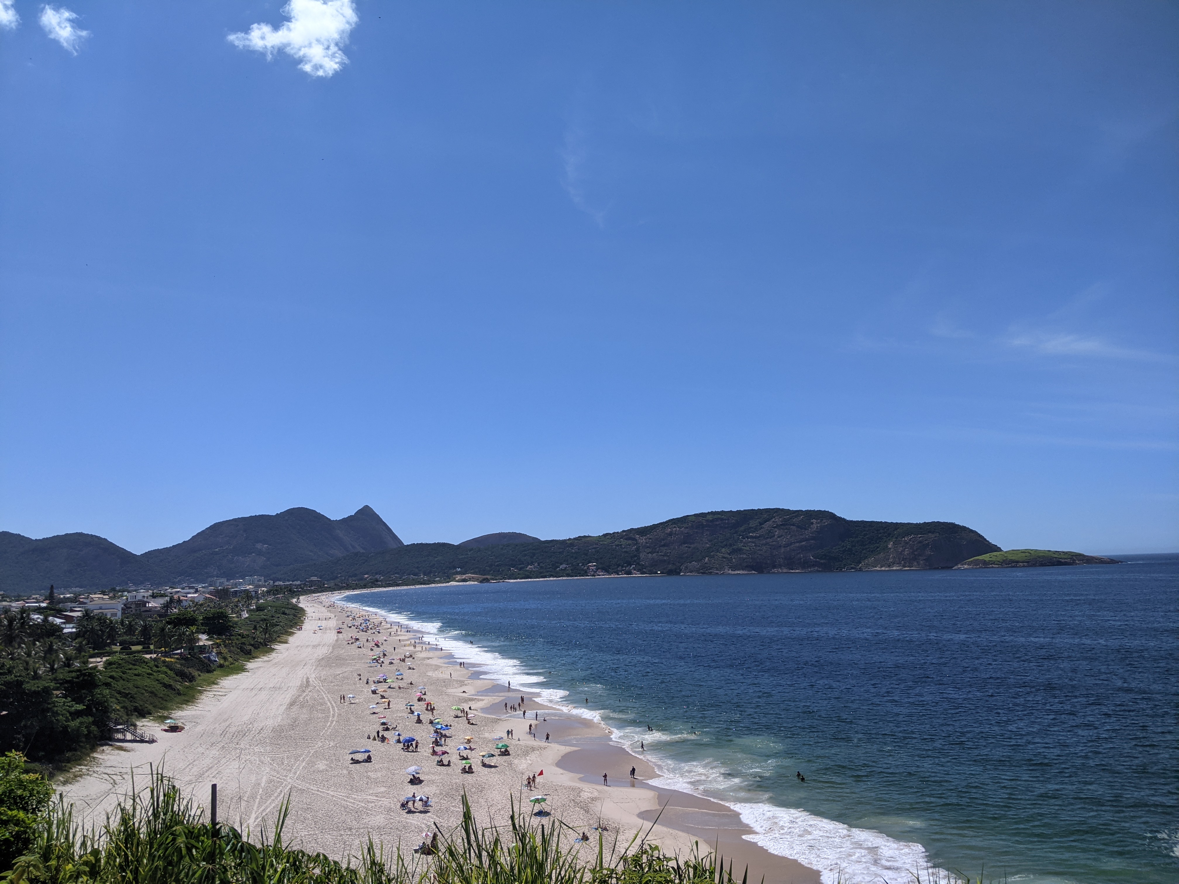 Wide crescent beach backed by green mountains and a headland near Rio de Janeiro