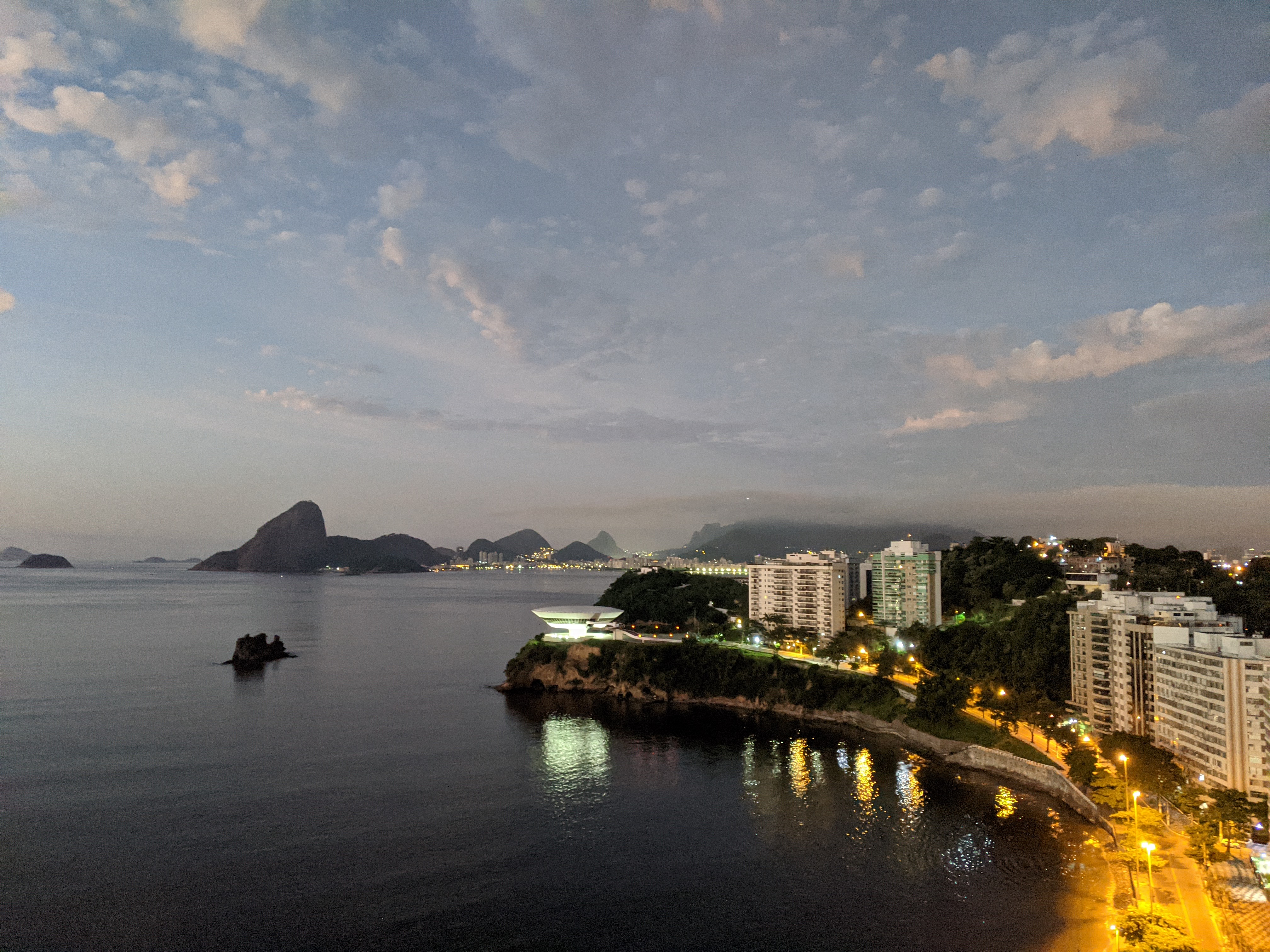 Dusk over Guanabara Bay with Sugarloaf Mountain in the distance and city lights along the shore