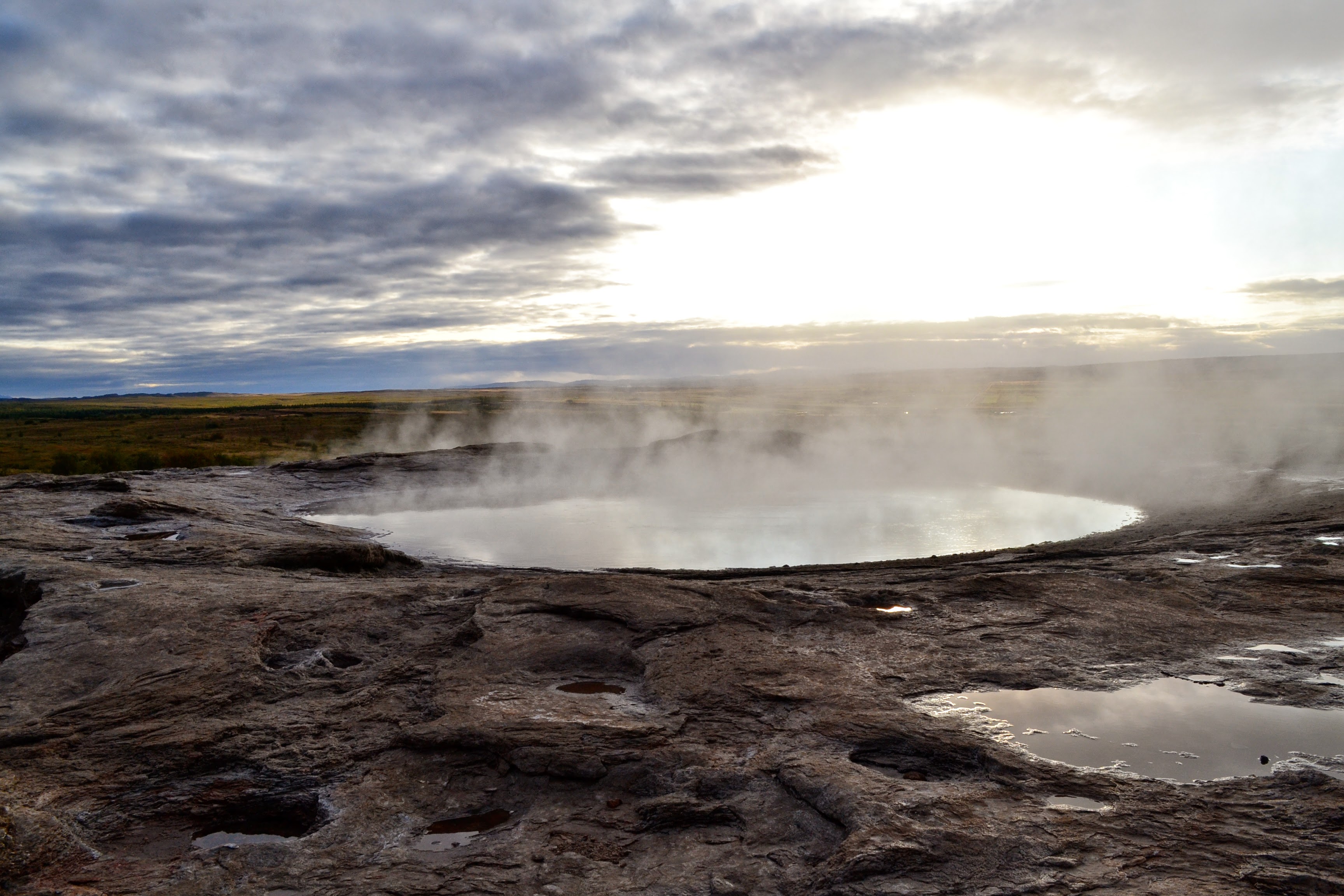 Steaming geothermal pool under a bright sky in Iceland