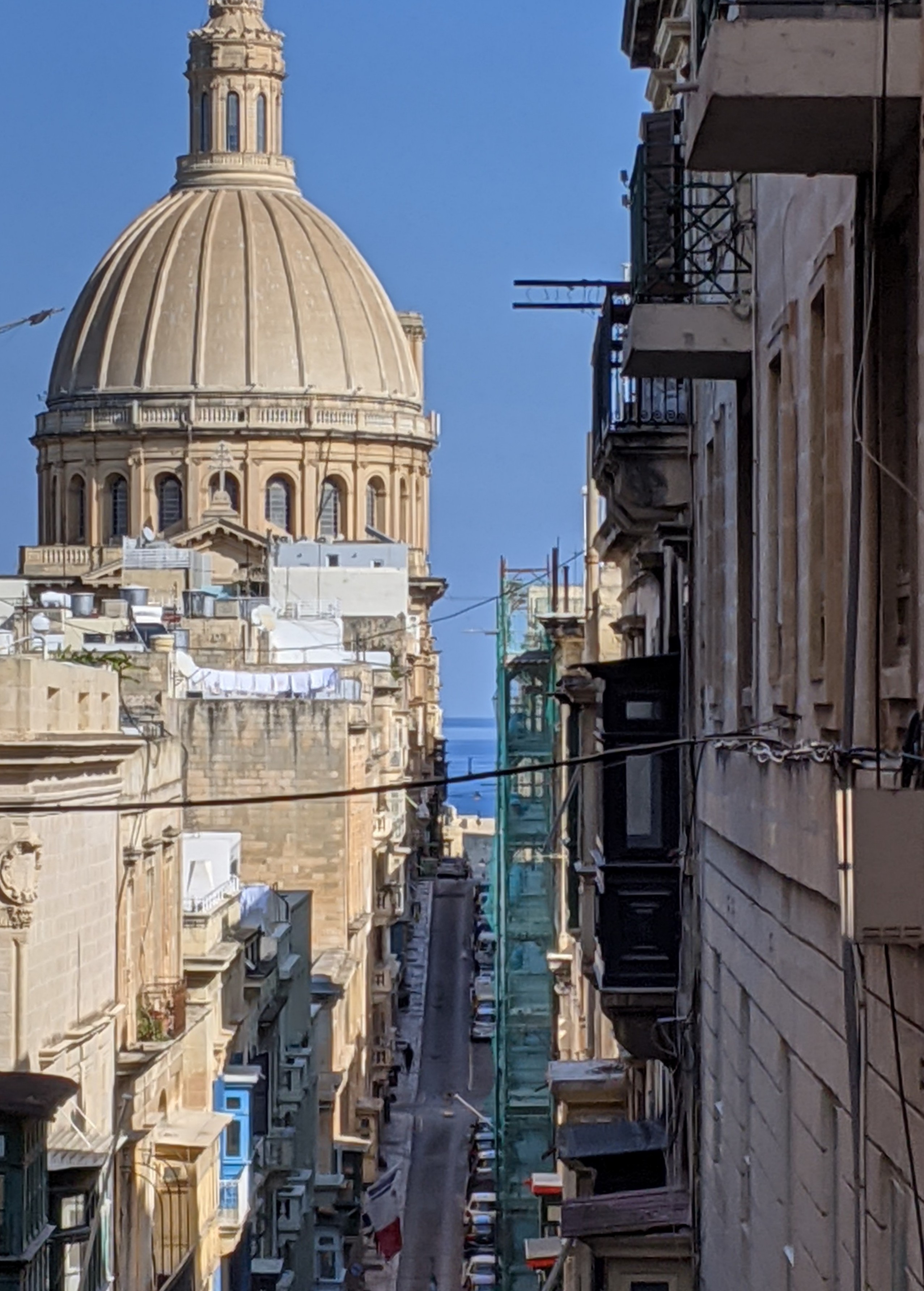 Valletta dome and narrow street with the sea in the distance