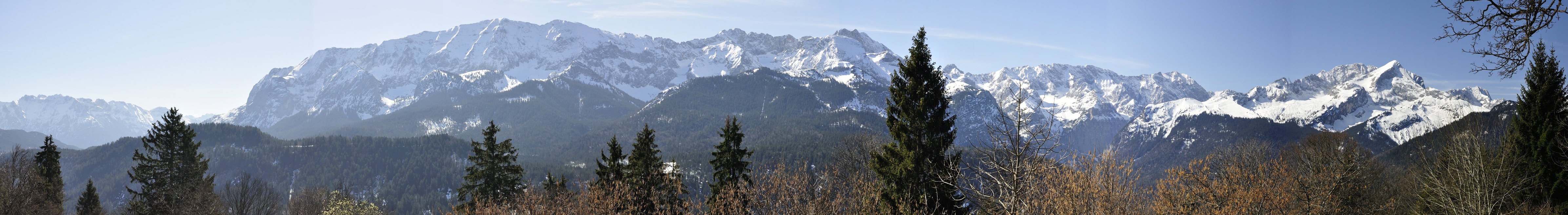 Panoramic view of snow-covered Alpine peaks above forests near Mittenwald